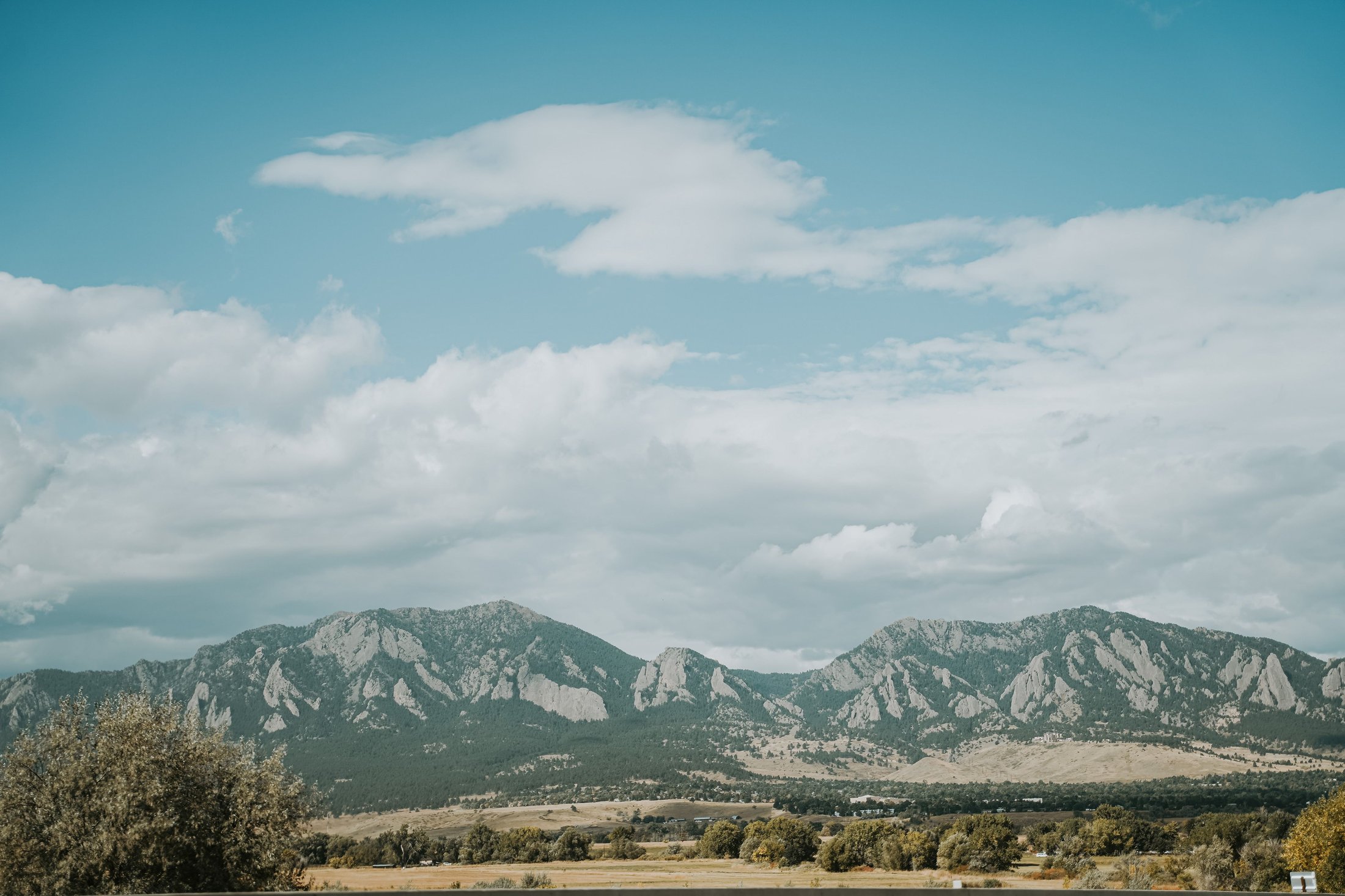 Flatirons and meadow under blue sky in Boulder